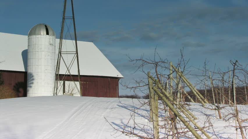 Shadow of a windmill travels across a silo as the full moon rises in the background, near an apple orchard. - HD stock footage clip