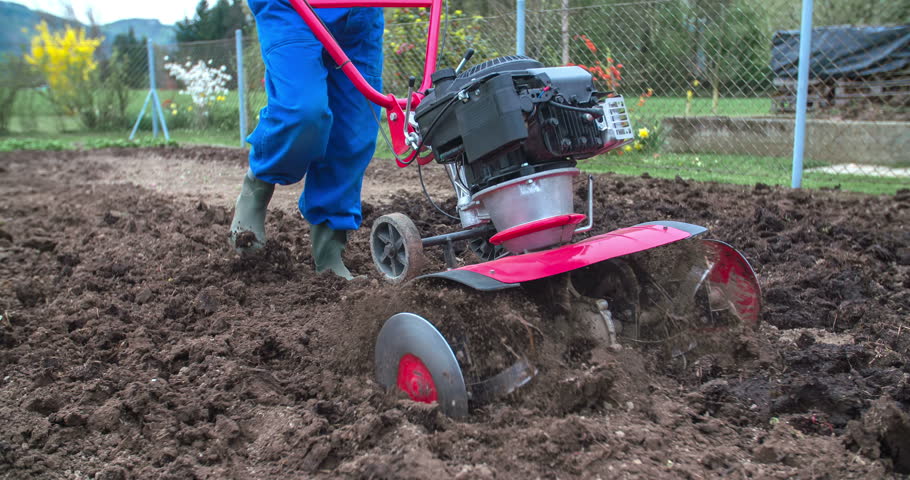 Plowing The Soil With Handheld Machine. Person Working On Own Garden 