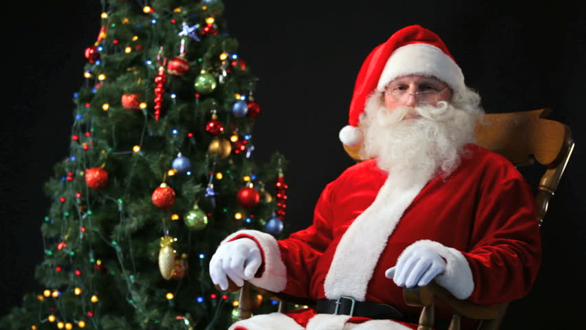 Santa Claus Sitting In A Rocking-chair With A Christmas Tree In The