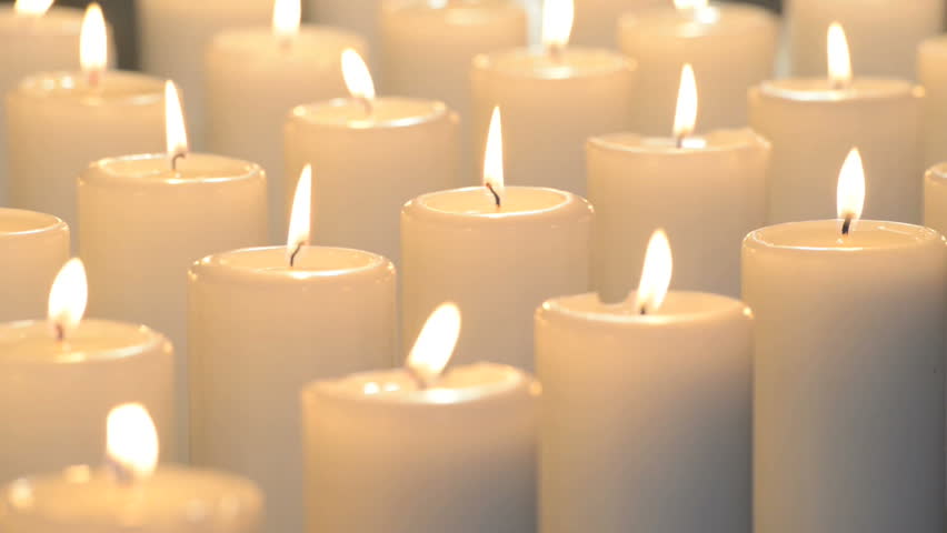 Nicely Lit Dolly Shot Of White Candles Burning With Soft Candle Light. Aligned In Long Lines ...