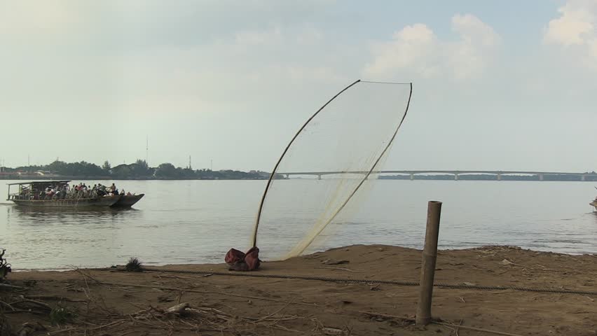 Cambodia   - november 2013  : Ferry boats passing each other near the pier; Fishing net on the riverbank in the foreground - HD stock footage clip