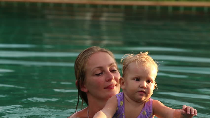 One Year Baby Girl With Her Mother In The Pool Squirting At Sunset